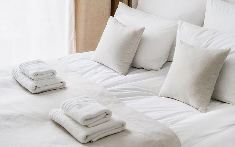 Fresh white bedlinen and towels on bed